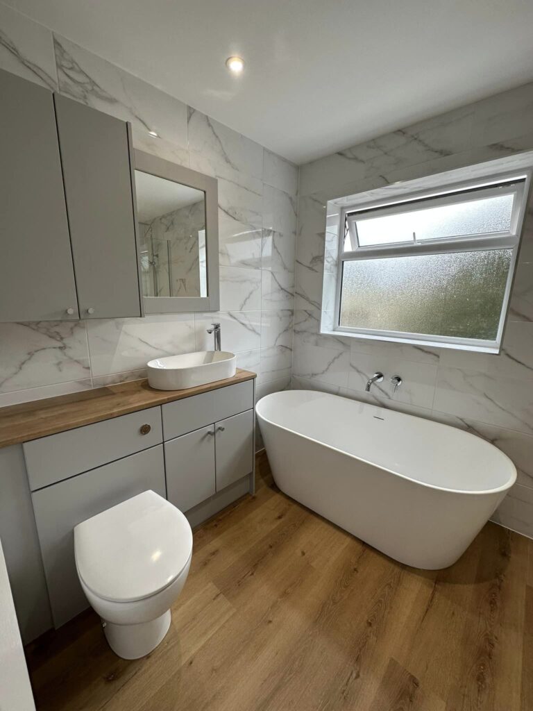 A modern bathroom toilet, sink and bath with a hardwood floor