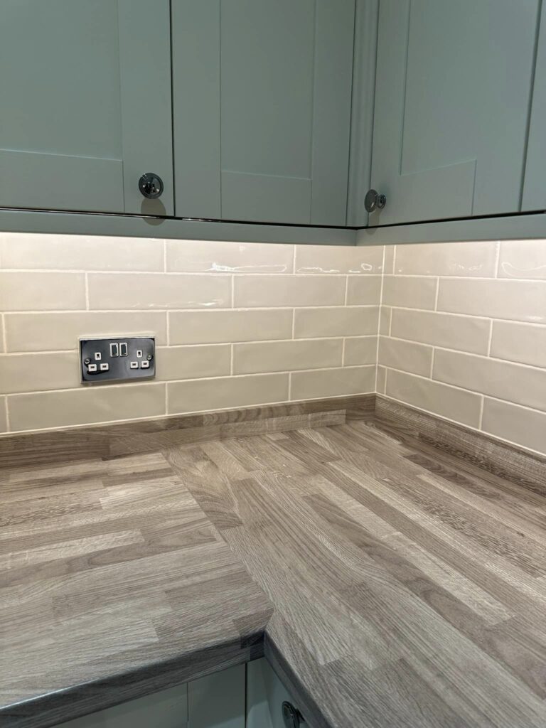 Close up of the corner of modern kitchen units with white cupboard doors and grey wooden countertops